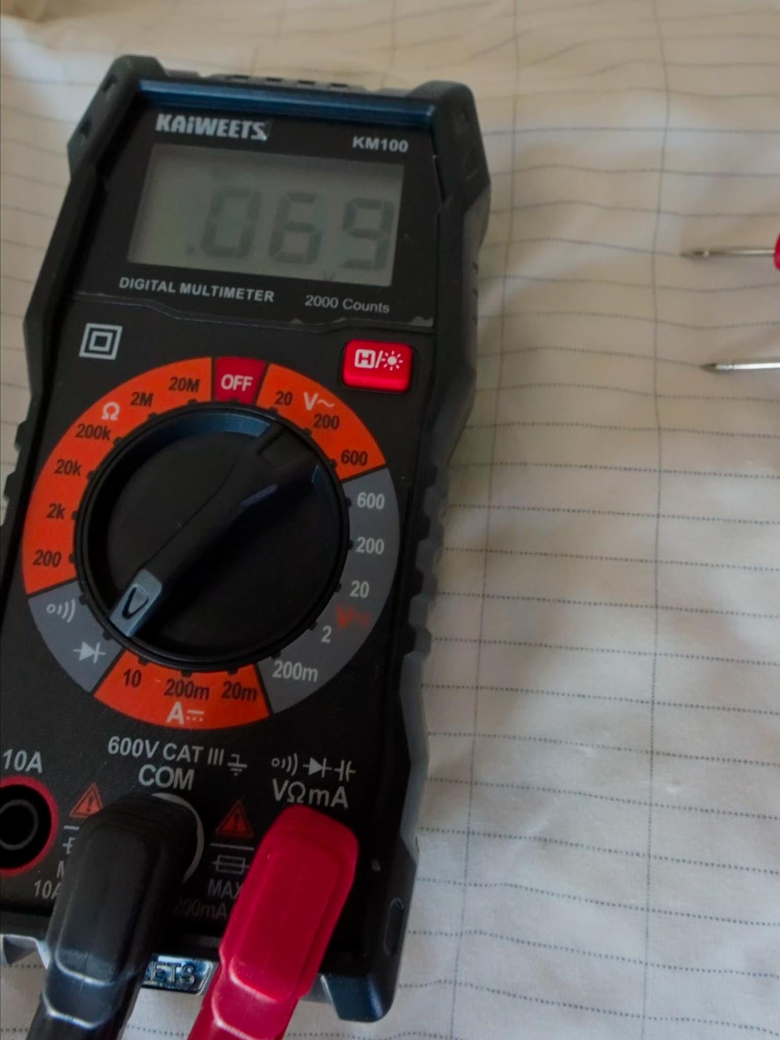 Multimeter showing reduced voltage on grounded sheet