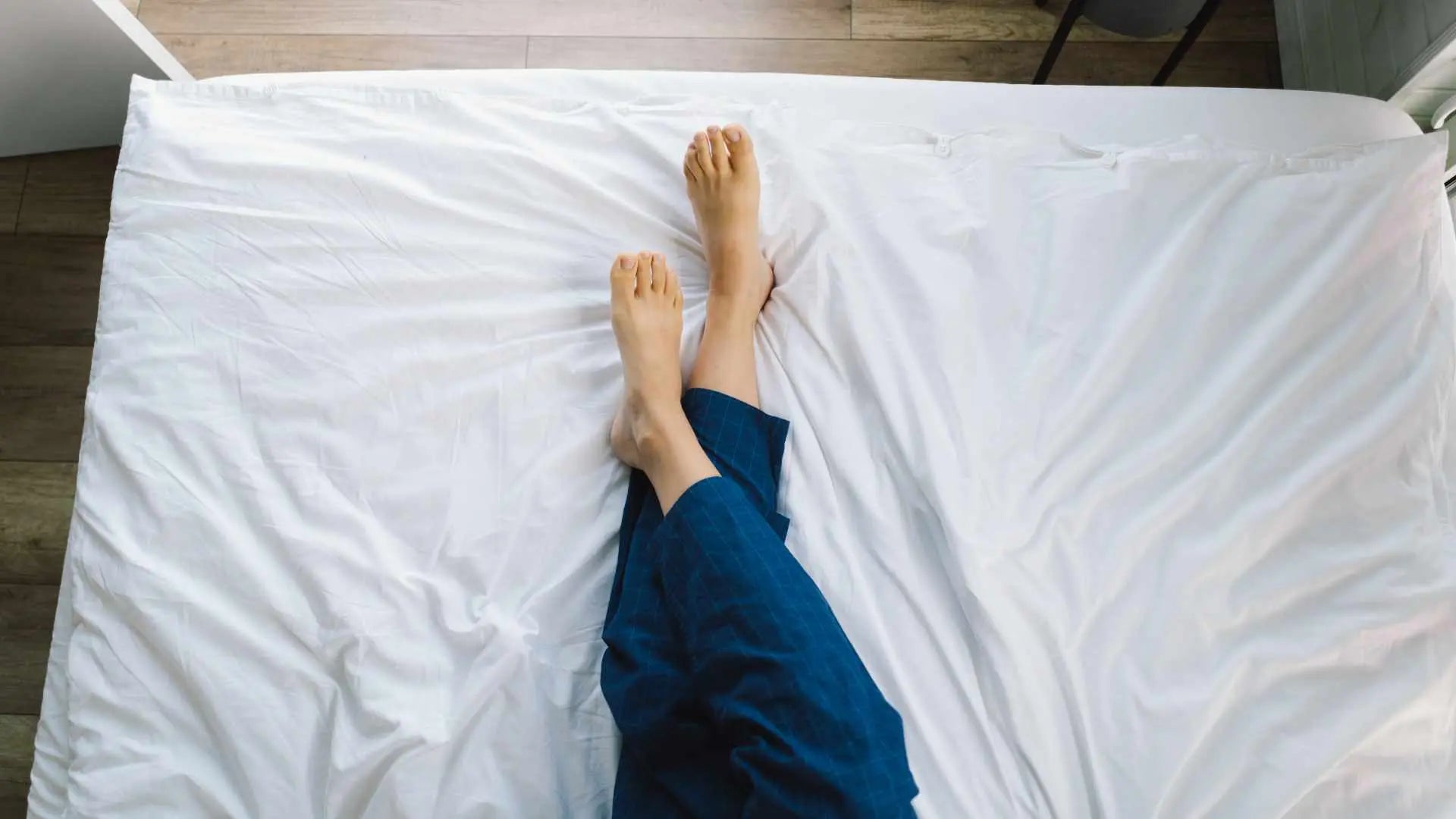 Person resting bare feet on a grounding sheet in bed to support sleep and overnight grounding