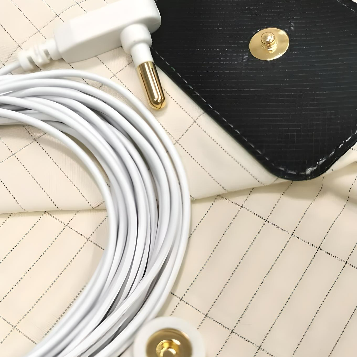 Close-up of grounding mat kit with white connection cable, grounding plug, and snap connector on conductive sheet fabric