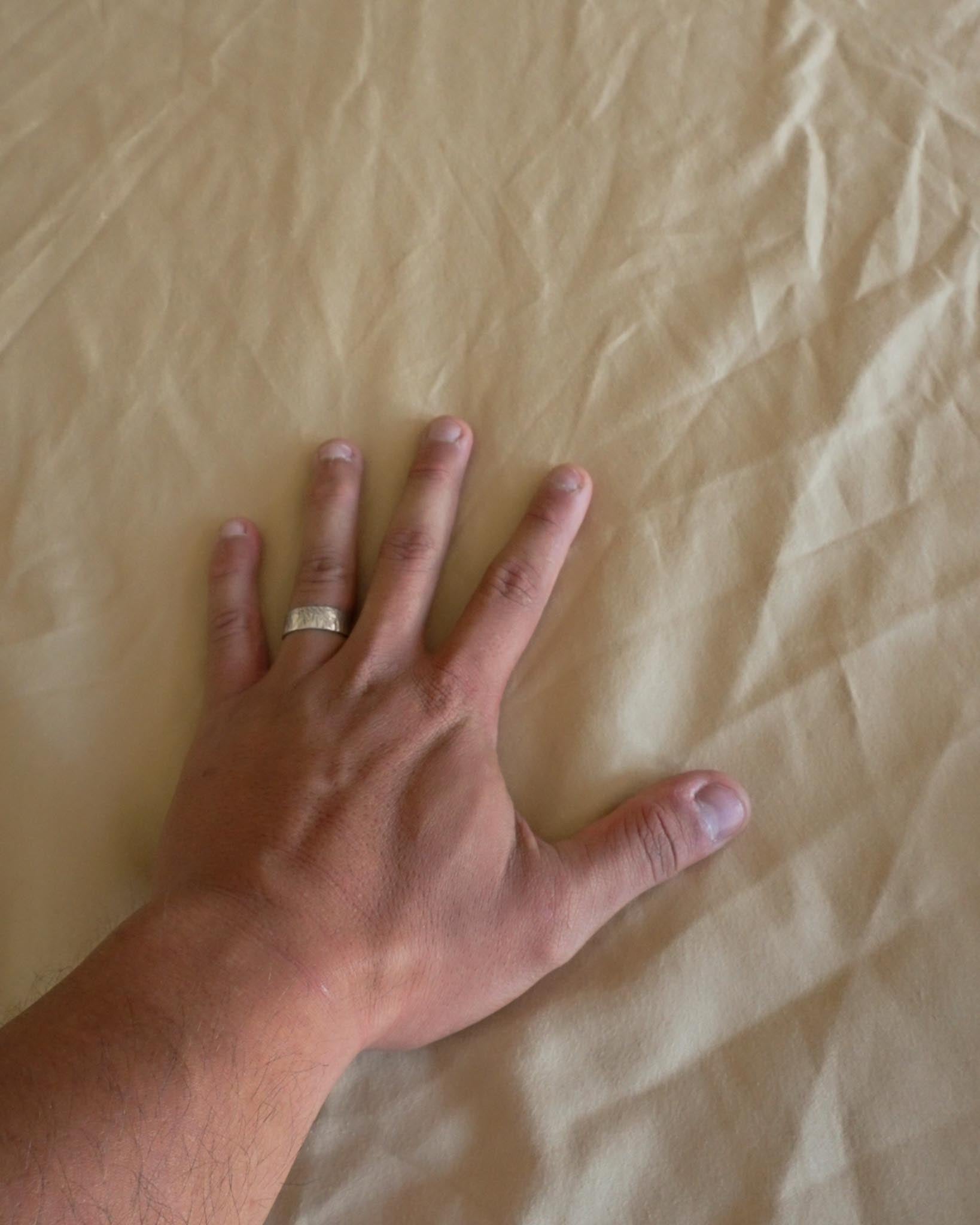 Hand resting on light-colored bed sheet demonstrating grounding contact surface