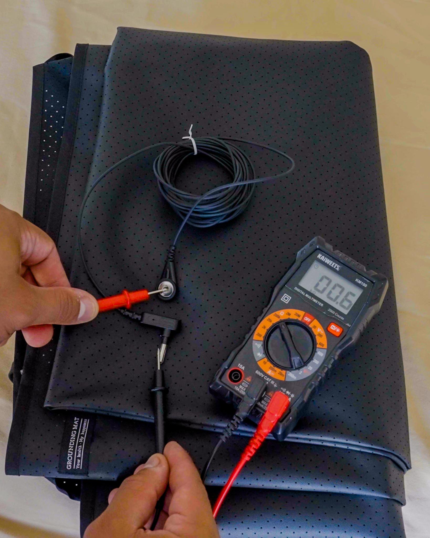 Testing grounding mat cable connection showing 0.06V reading on digital multimeter