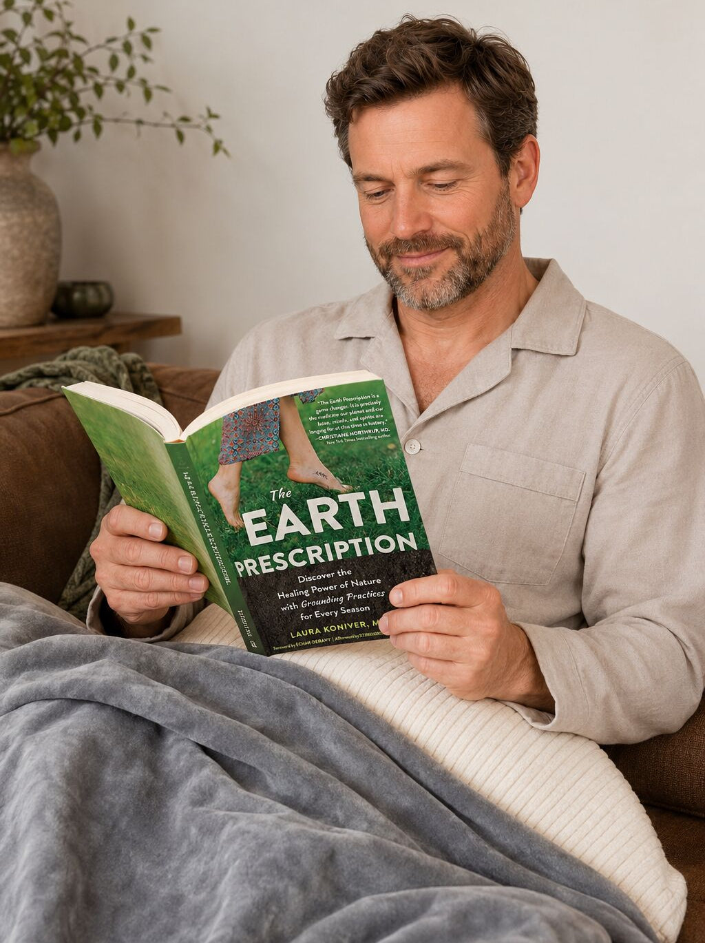 Man reading 'The Earth Prescription' book in a grounding blanket