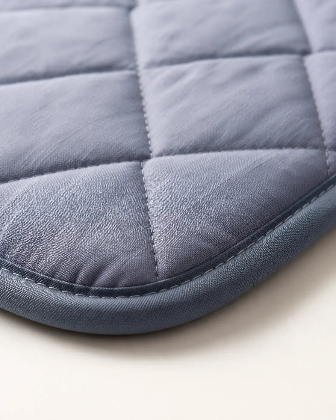 Close-up of the navy quilted pad's diamond stitching