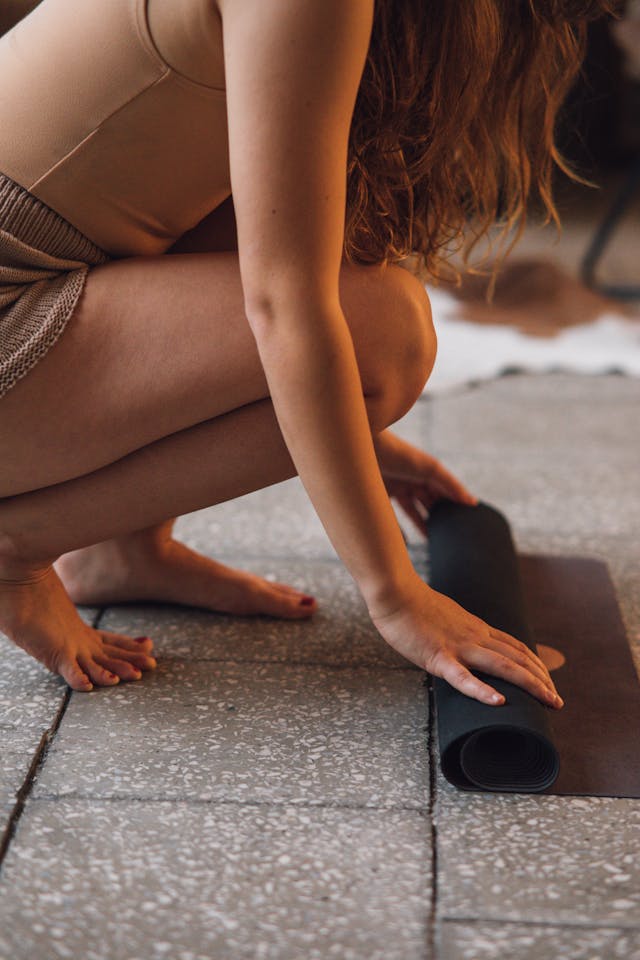 Person rolling out a grounding yoga mat on a tiled floor