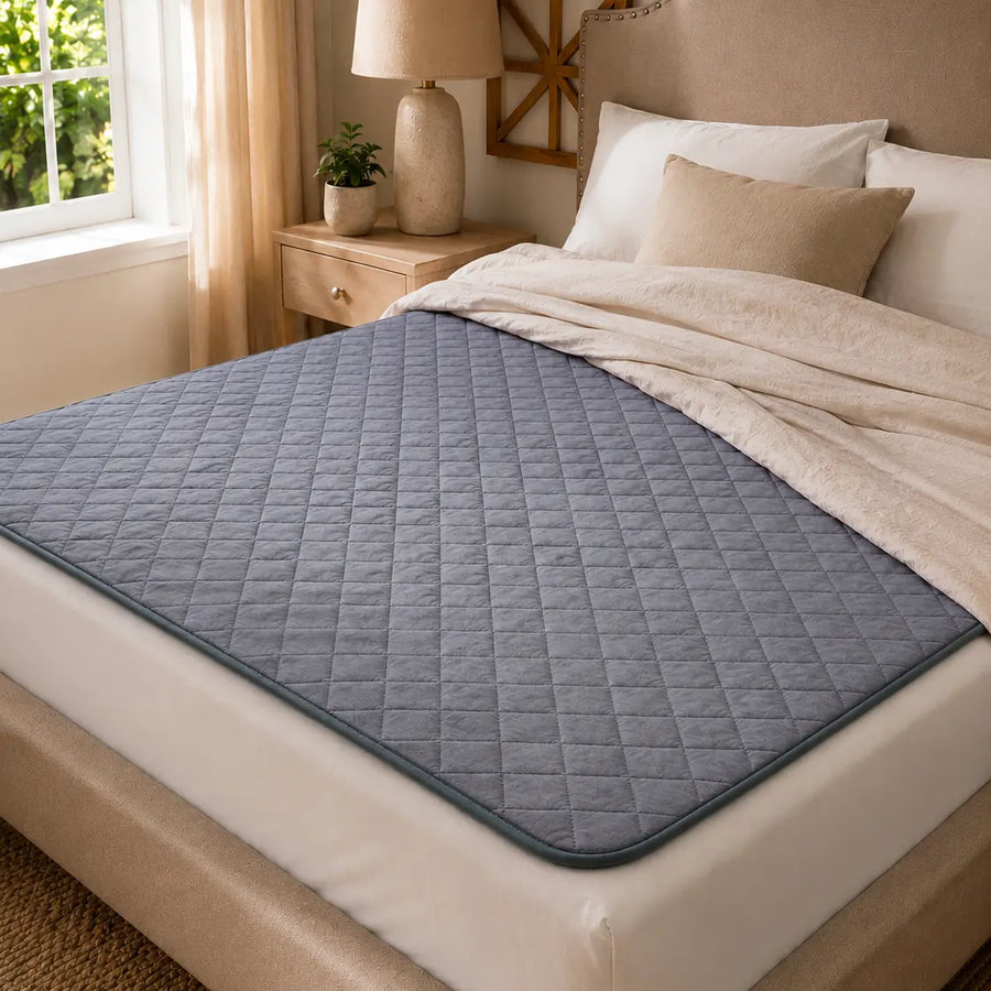 Navy quilted grounding pad laid across a mattress