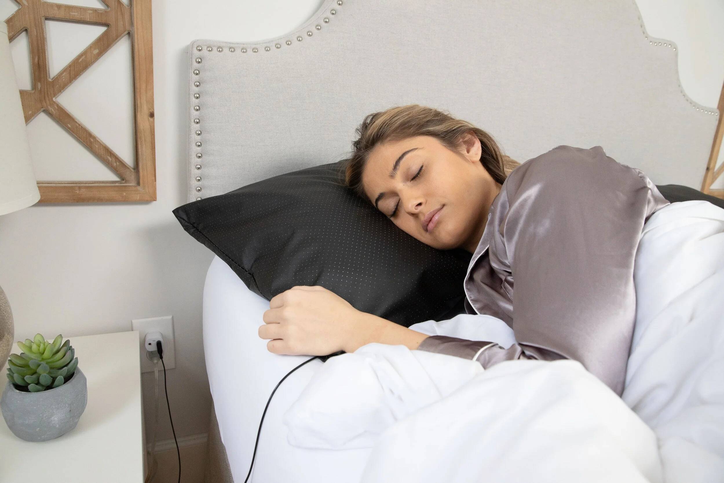 Woman using a neck and shoulder massager in bed